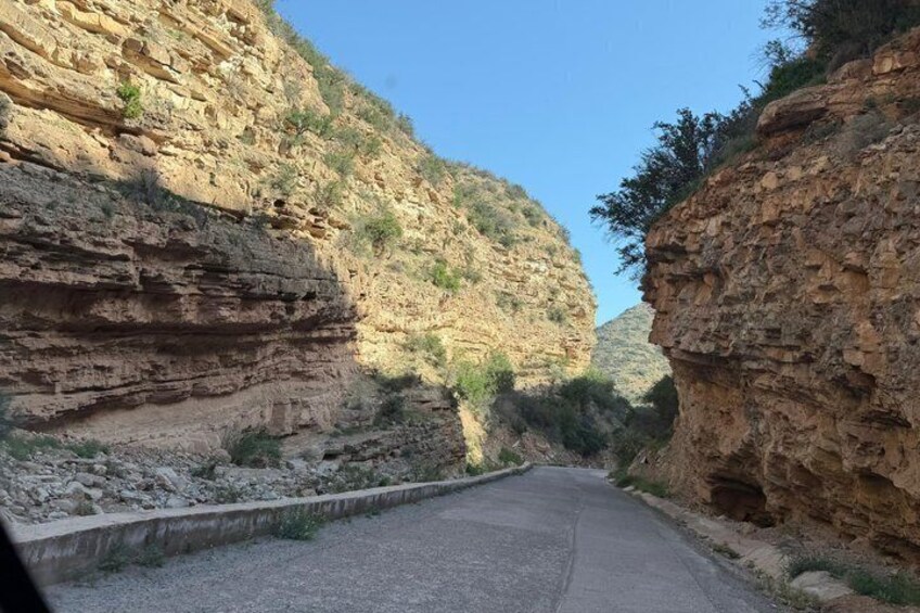 A narrow road winding through a canyon with rocky cliffs on either side. 2