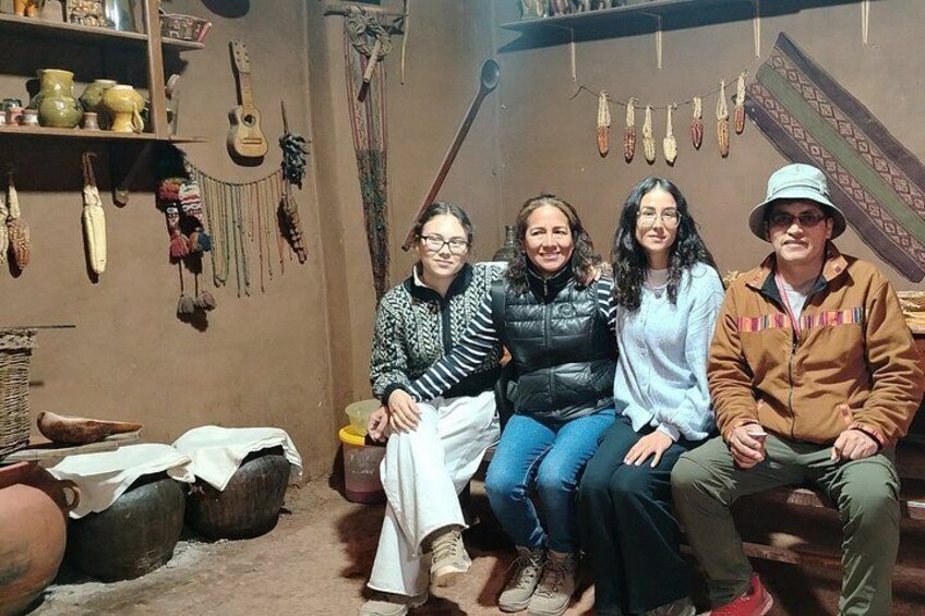 Four people sitting on a bench in a room with pottery and textiles on the walls. 2