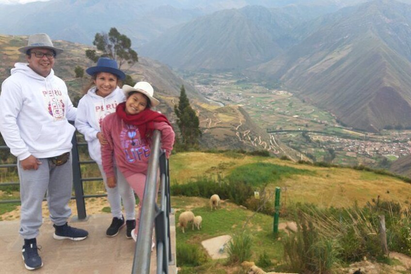 A group of people standing on a viewing platform overlooking a valley with mountains in the background. 5