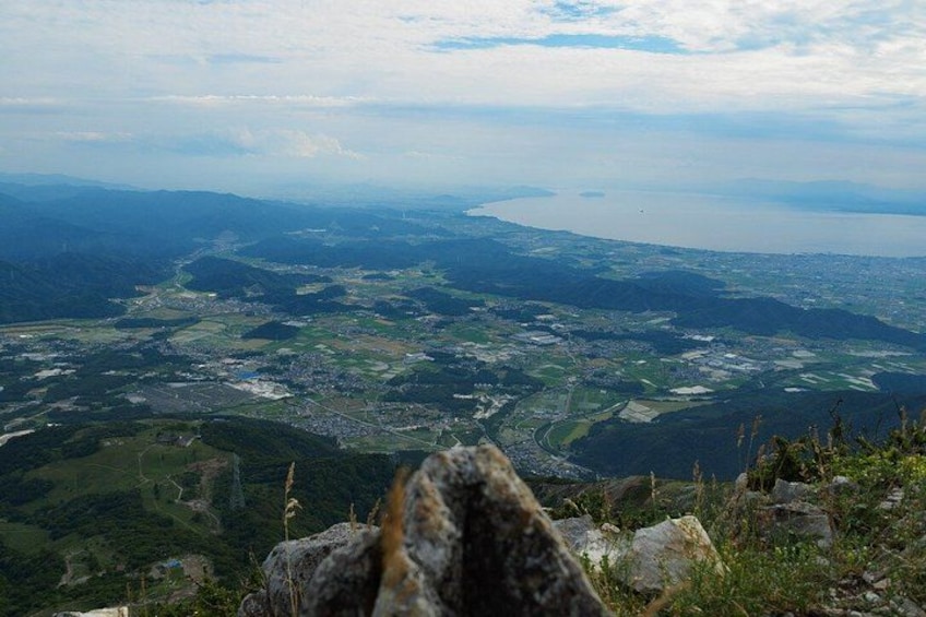 A mountainous landscape with a valley, a river, and a distant body of water. 3