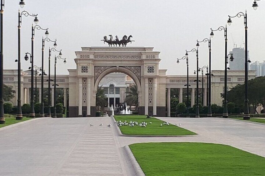 An ornate archway with a horse statue, surrounded by a well-maintained lawn and street lamps. 3