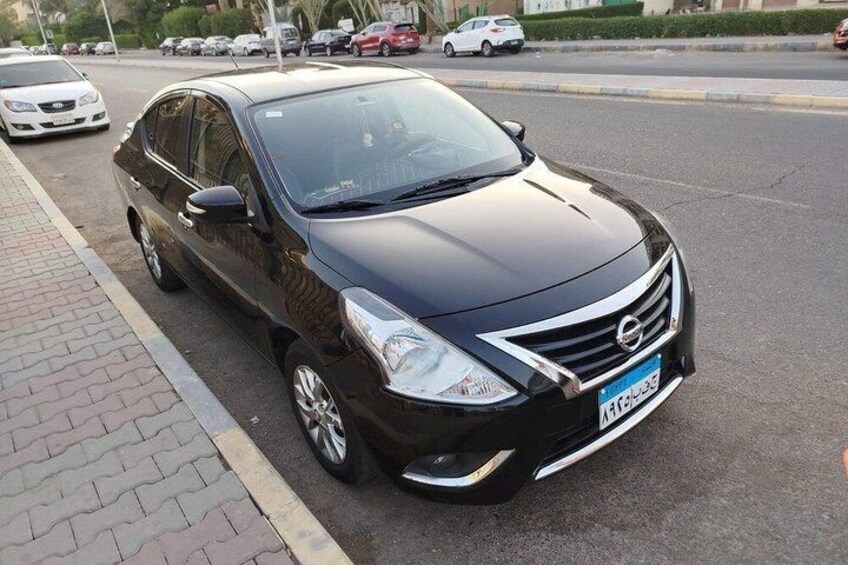A black sedan parked on the side of a road with a curb. 2