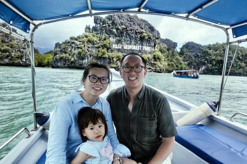 A boat with a canopy, a rocky island with a sign in the background, and calm water. 3