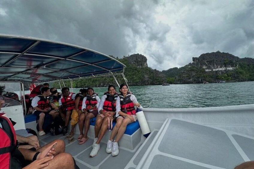 A boat with passengers wearing life jackets, a canopy, and a body of water with hills in the background. 4