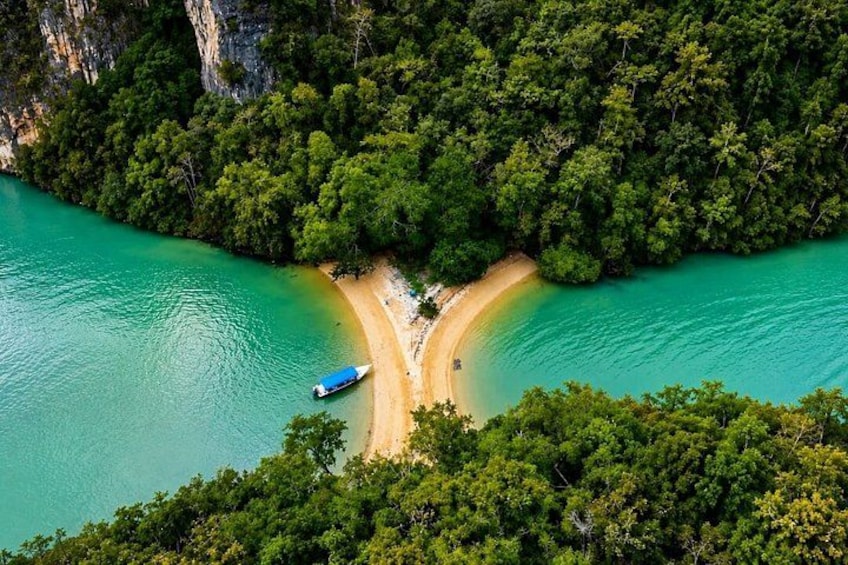 A turquoise river, a sandy beach, dense green forest, and a small boat. 1