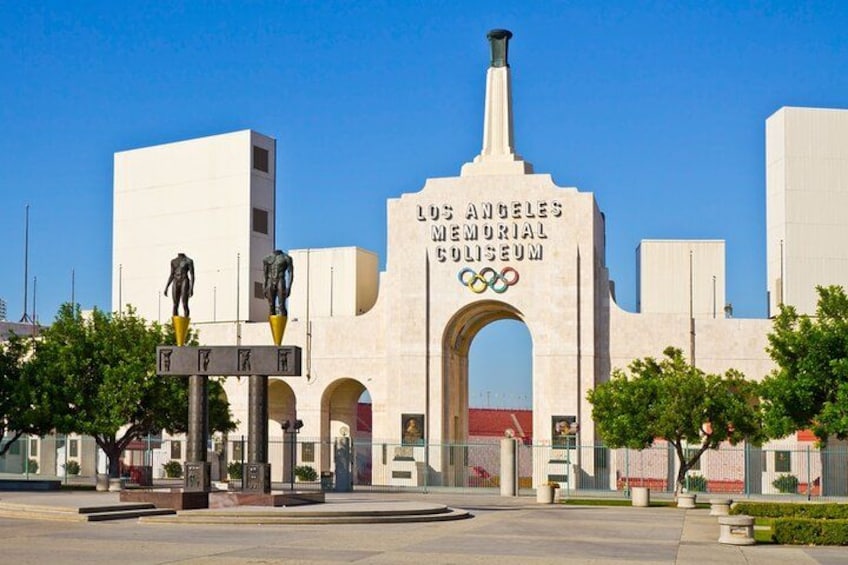 The Los Angeles Memorial Coliseum with Olympic rings, a statue, and a large archway. 2