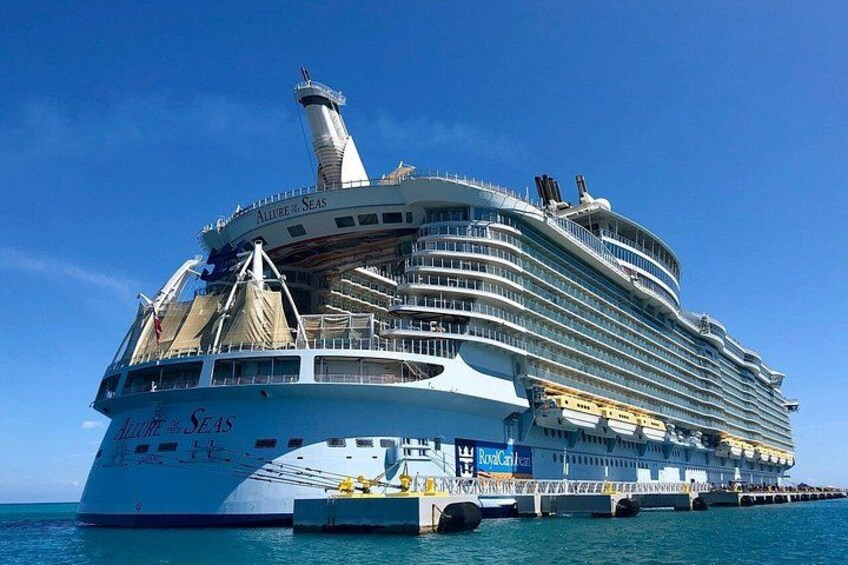 Een groot cruiseschip genaamd 'Allure of the Seas' ligt aangemeerd in een haven. 1