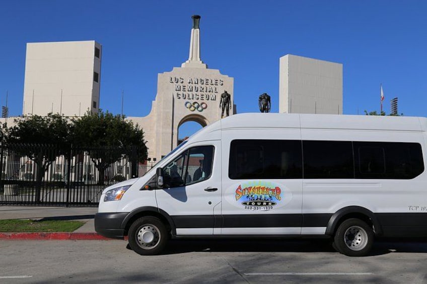 A white van parked in front of the Los Angeles Memorial Coliseum. 4