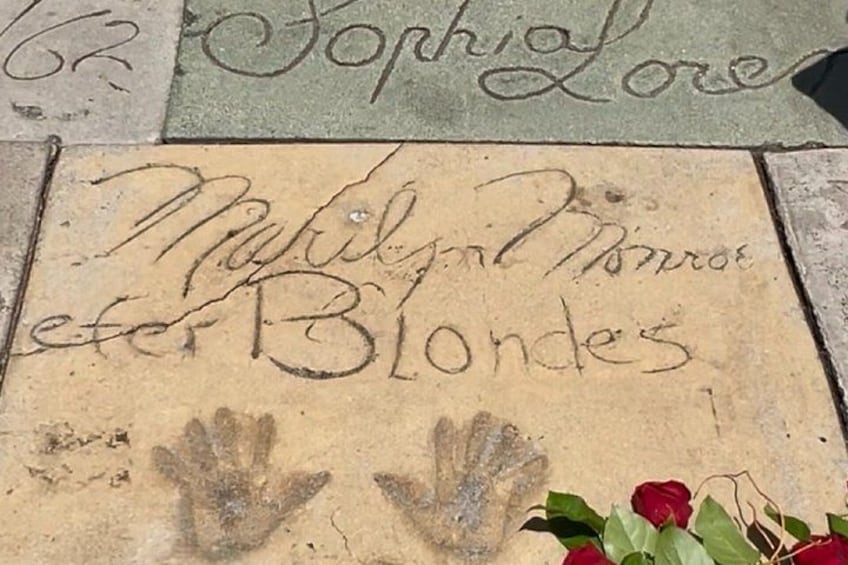 A sidewalk with engraved names and a handprint. 5