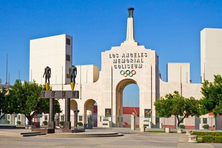 The Los Angeles Memorial Coliseum with a large archway and Olympic rings logo. 5