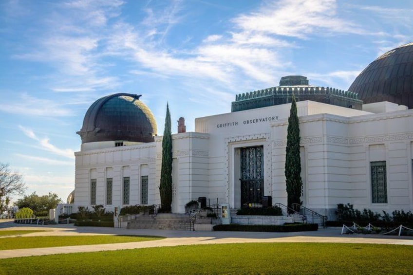 The Griffith Observatory with a large dome and a smaller dome, surrounded by a well-maintained lawn and a clear sky. 3