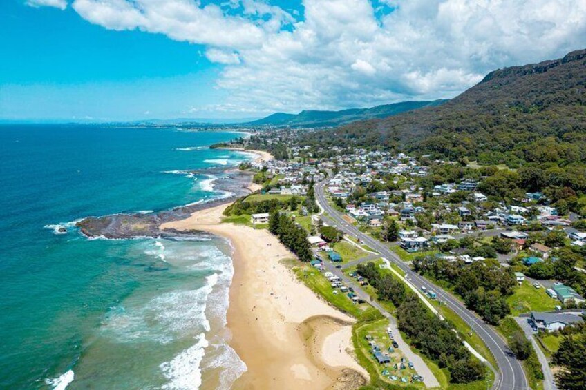 A coastal town with a beach, ocean, and a mountain in the background. 2