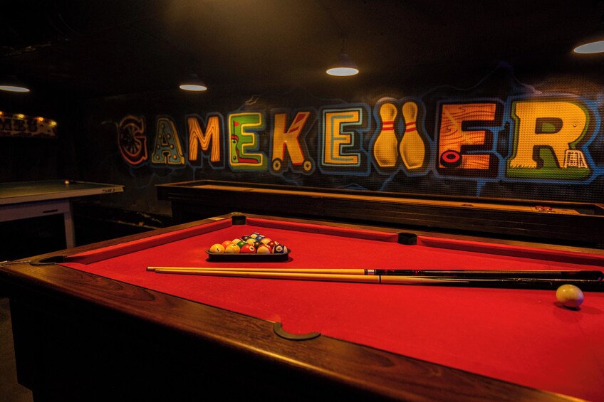 A pool table with balls and cues, and a neon sign spelling 'GAMEKIER' on the wall. 1