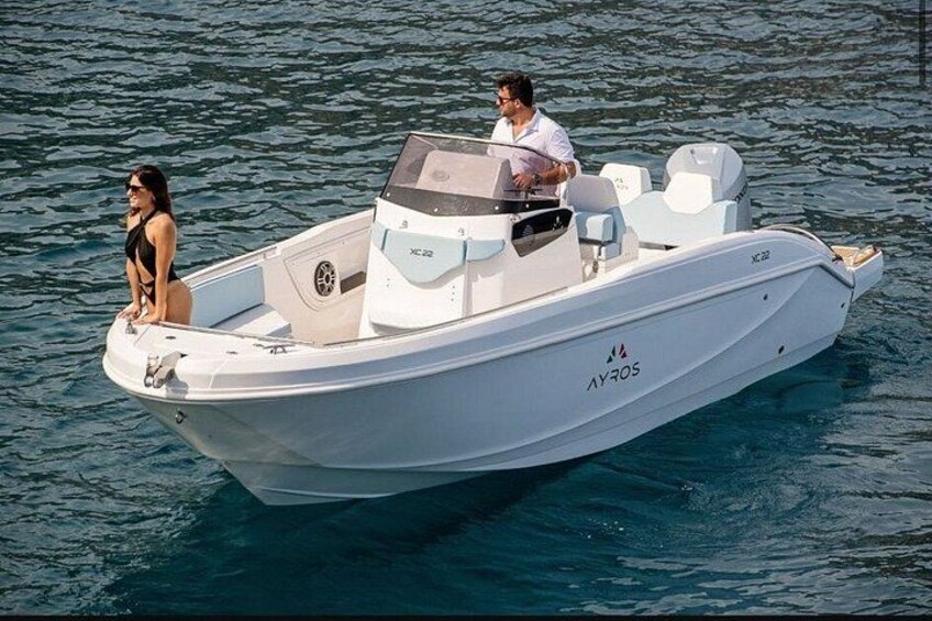 A white motorboat with two people on board, one standing at the bow and the other at the stern, on calm water. 5