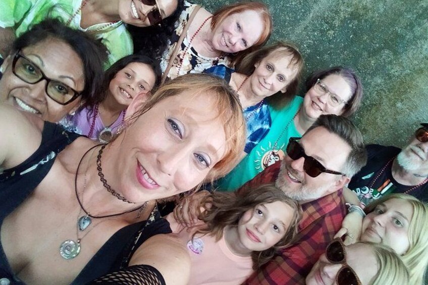 A group of people in close proximity, some wearing casual clothing, with a concrete wall in the background. 2
