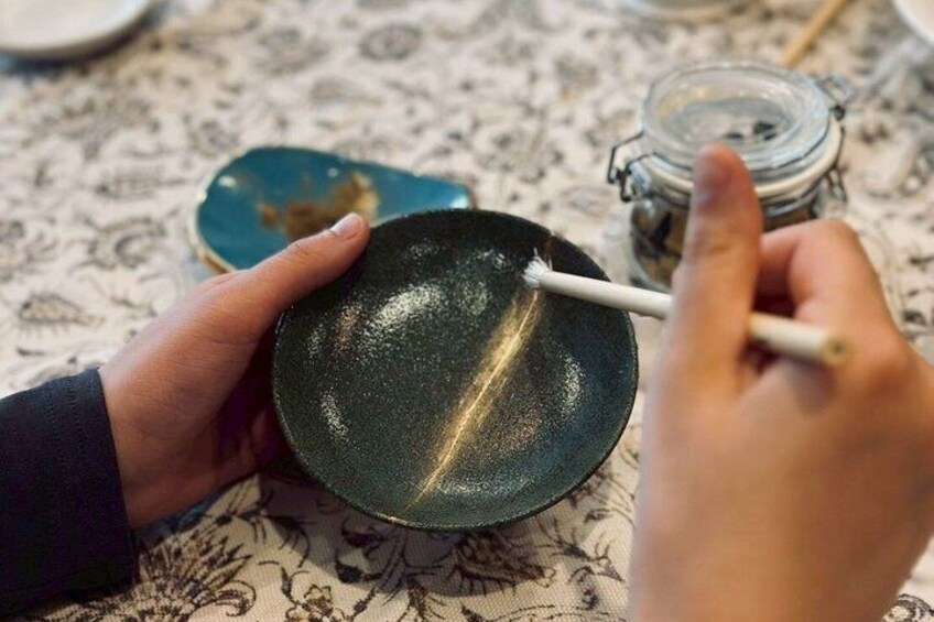A person holding a black pan with a brush. 3