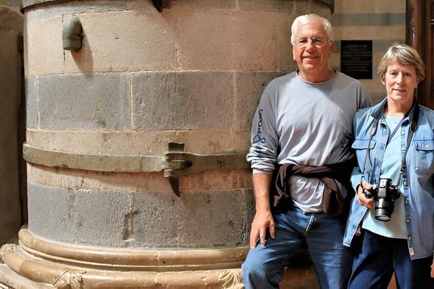 A large stone structure with a metal door, a person holding a camera, and another person standing beside it. 5