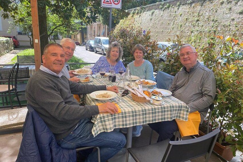 A group of people dining outdoors at a table with a checkered tablecloth. 2