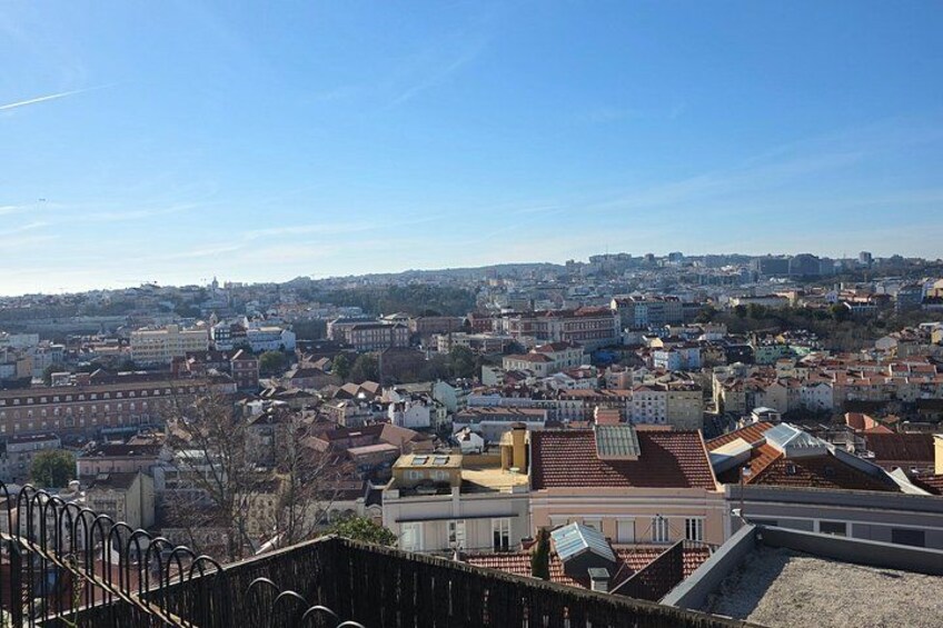 A cityscape with a mix of historical and modern buildings, a clear sky, and a distant view of the city extending to the horizon. 5