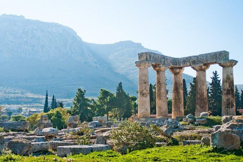 Ancient ruins with columns, a mountainous backdrop, and scattered stones. 4