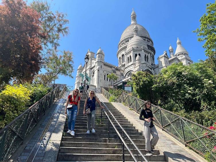 A group of people ascending a stone staircase towards a large domed building with multiple towers. 3