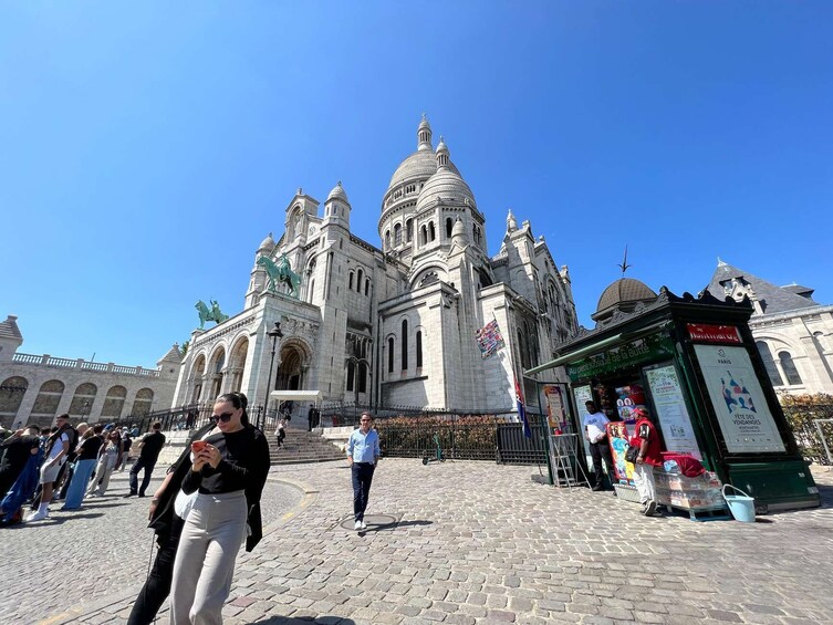 A historic building with a dome and statues, a cobblestone plaza, and a small kiosk. 2