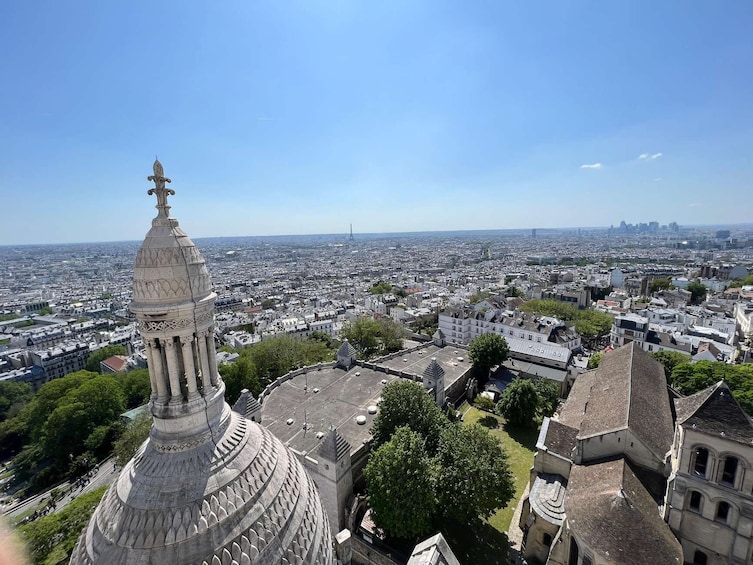 A domed building with a spire, surrounded by urban buildings and a clear sky. 5