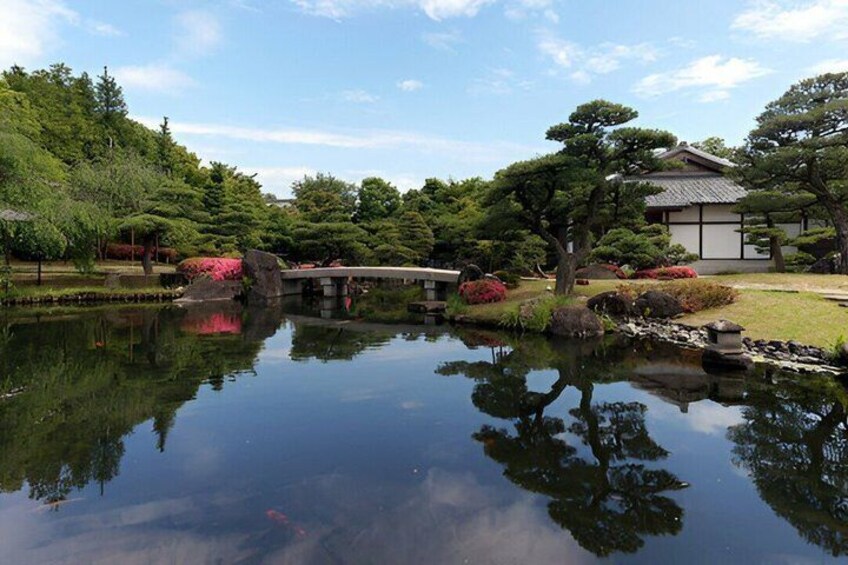 A tranquil pond with a bridge, surrounded by lush greenery and traditional Japanese architecture. 4