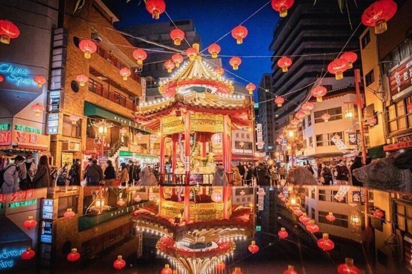 A traditional Chinese pavilion with red lanterns, a reflective water surface, and surrounding shops. 5