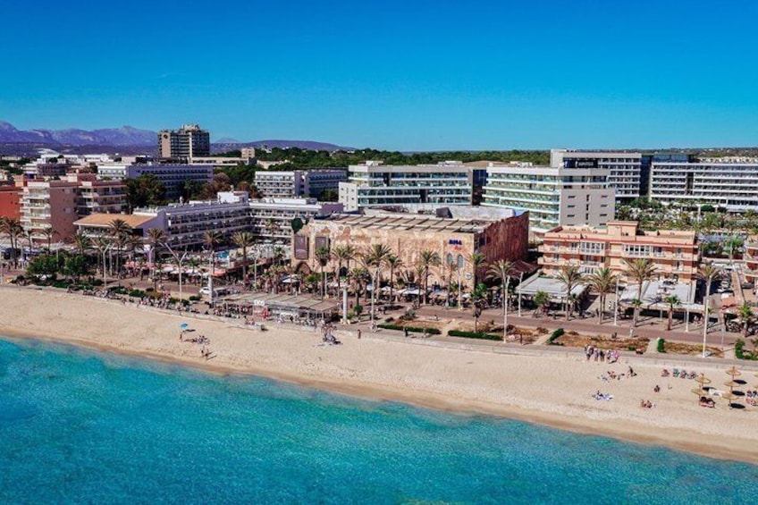 A coastal cityscape with a beach, palm trees, and modern buildings. 2