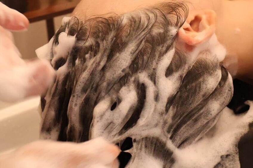 A person washing hair in a bathtub with soap suds. 4