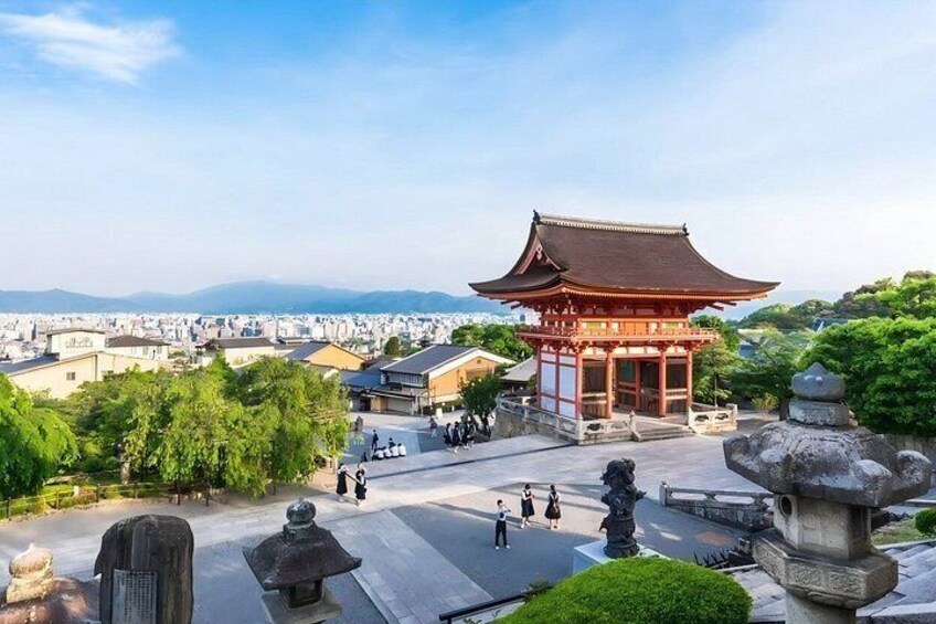 A traditional Japanese pagoda with a red roof, surrounded by greenery and stone lanterns, overlooking a cityscape. 2