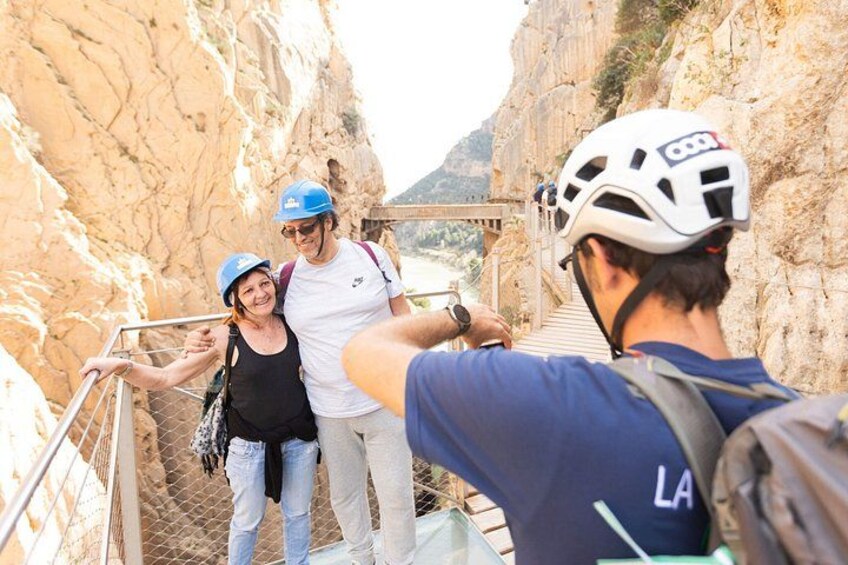 A group of people wearing helmets and hiking gear, standing on a metal staircase in a rocky canyon. 5