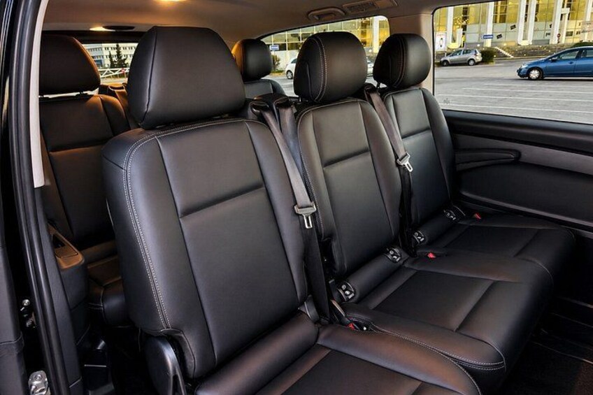 A car's interior with black leather seats and a visible seatbelt. 3
