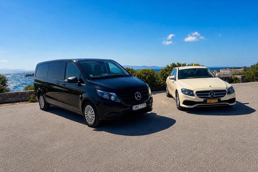 A black Mercedes-Benz Sprinter van and a white Mercedes-Benz sedan parked on a coastal road with a clear sky. 4