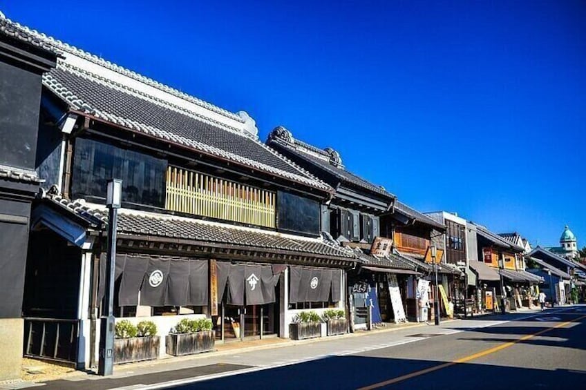A street lined with traditional buildings, some with awnings, under a clear blue sky. 3