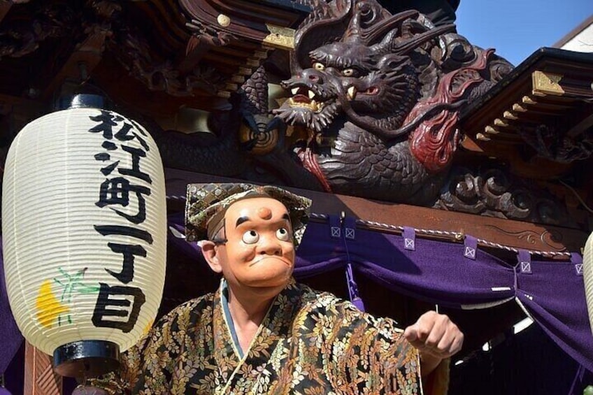 A person holding a traditional Japanese lantern with Chinese characters, standing in front of a building with ornate architectural details. 5