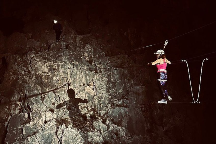 A person on a slackline in a rocky outdoor setting at night. 2