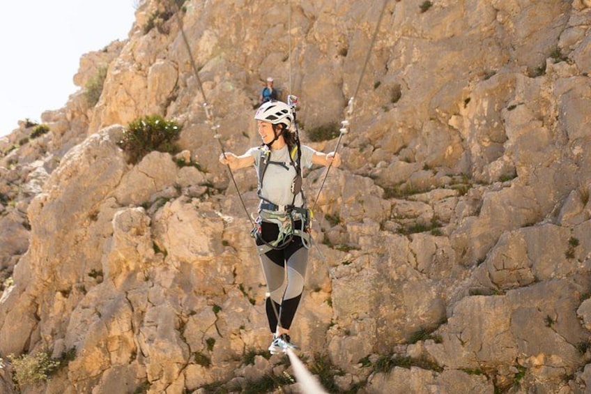 A person bungee jumping with safety harnesses against a rocky cliff backdrop. 5