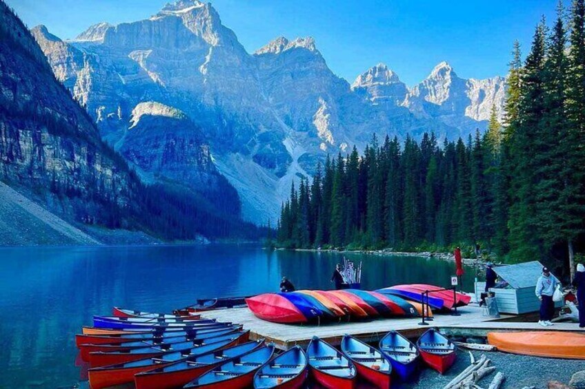 A lake with boats docked on a pier, surrounded by forest and mountains. 5
