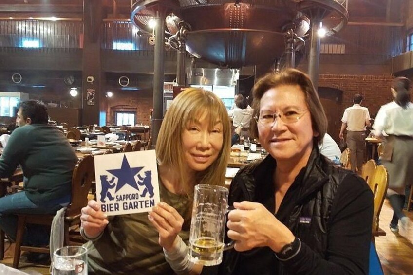 Two people holding a sign with a star and text, in a restaurant with tables and people dining. 4
