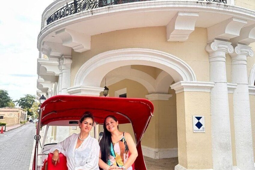 A red convertible parked in front of a building with white columns and an arched entrance. 1