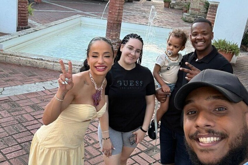 A group of people posing in front of a brick patio with a fountain. 2
