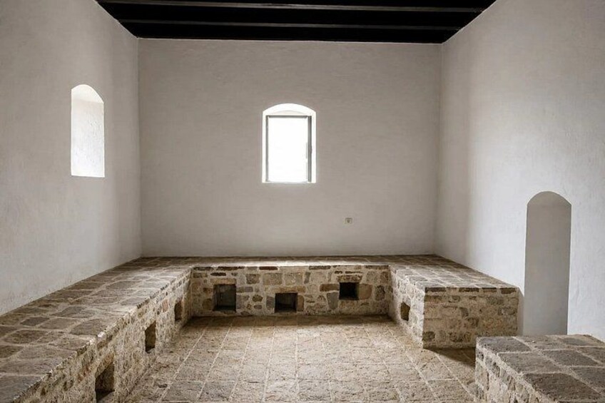A stone-walled room with a small window and a stone bench. 4