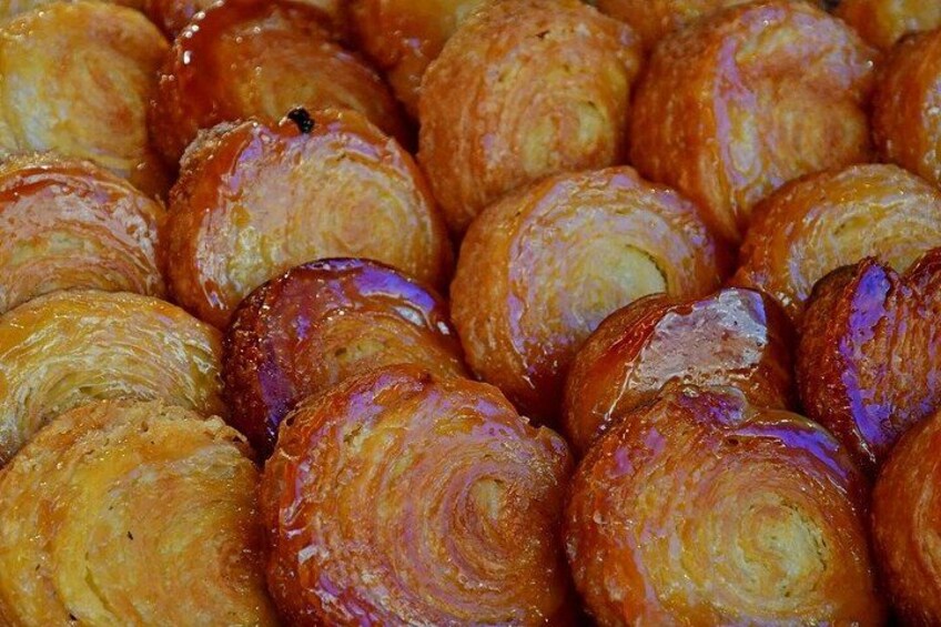 A close-up of glazed pastries, likely croissants, with a shiny, golden-brown surface. 3