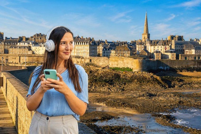 A person standing on a waterfront with a cityscape in the background. 1