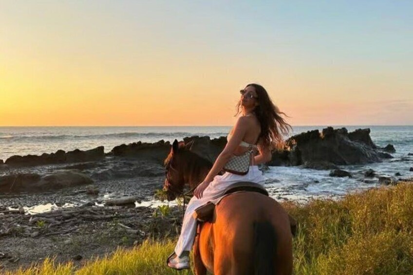 A person riding a horse on a rocky beach with the ocean in the background. 1