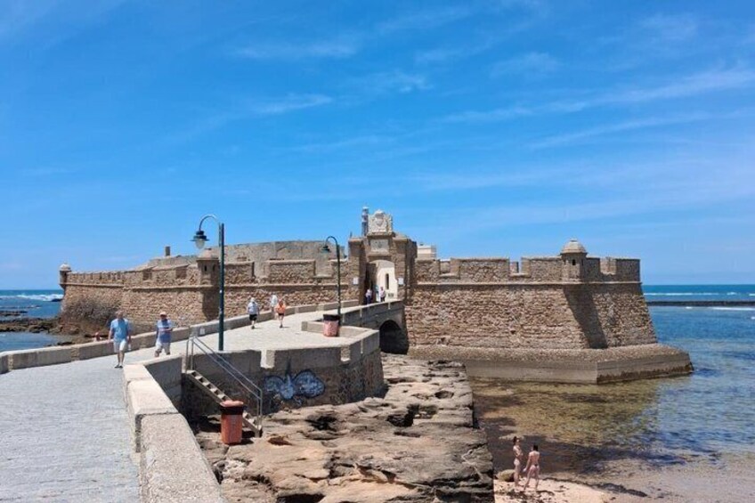 A historic fort with a stone wall, a staircase, and a clear blue sky. 1