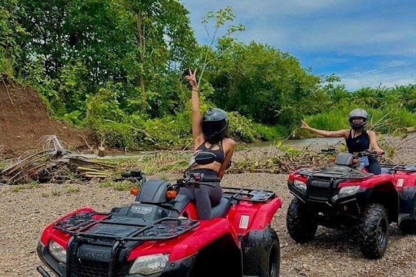 Two people on ATVs in a natural setting with trees and a dirt path. 5