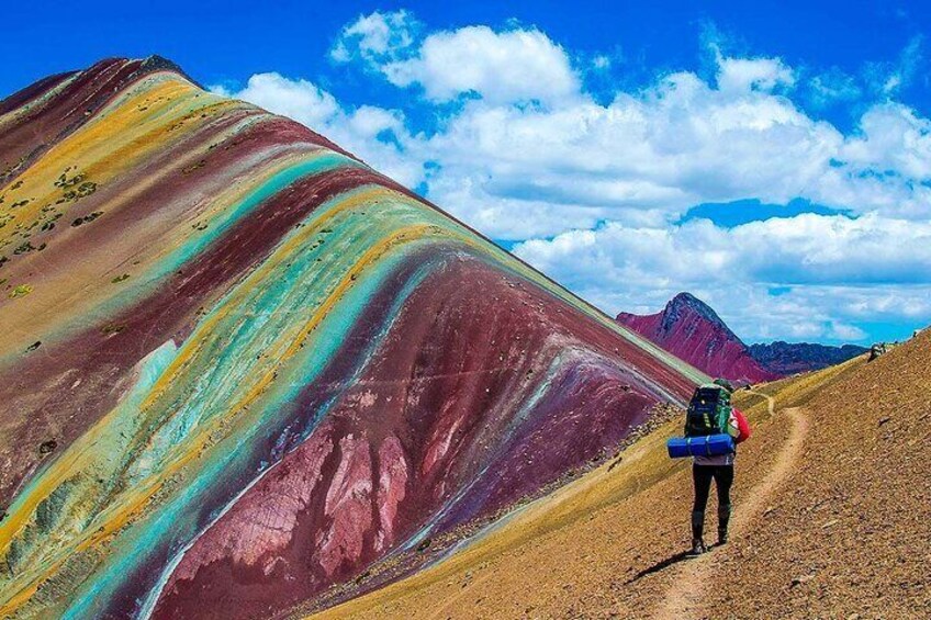 A hiker on a colorful trail with a mountain in the background. 2